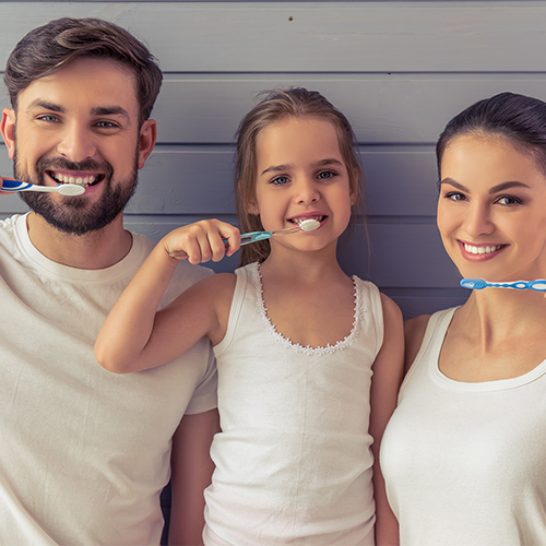 Una famiglia sorride con lo spazzolino in mano